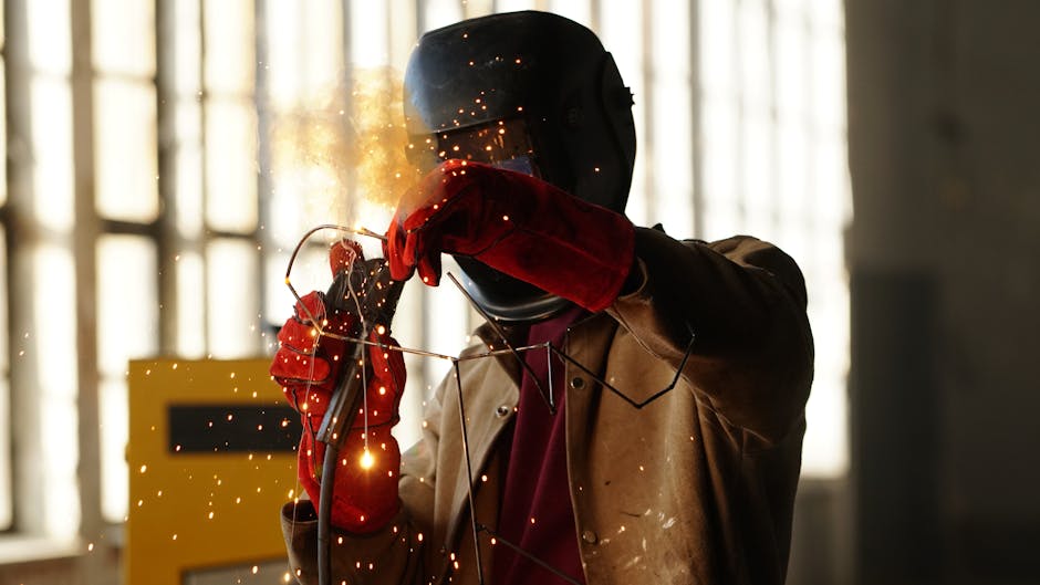 A welder working with sparks in a factory setting, showcasing safety gear and precision.