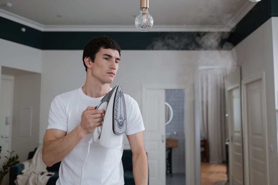 electric heated shirt - A man uses a steam iron on a white shirt indoors, highlighting daily household chores.