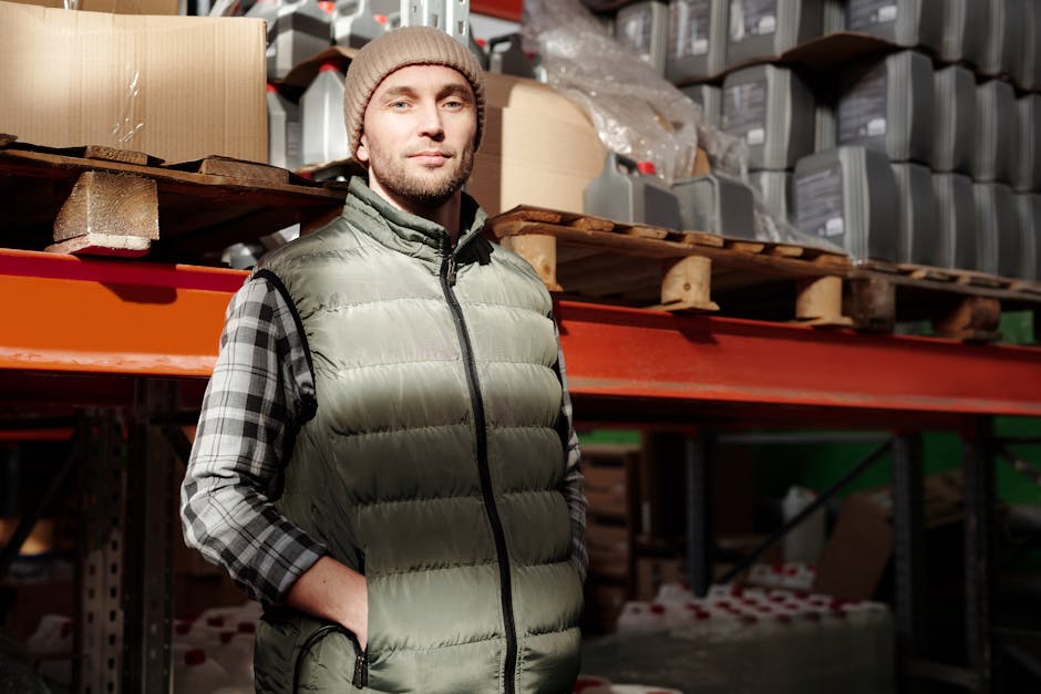 heated vest - A man in a green vest stands confidently in a warehouse, illuminated by natural light.