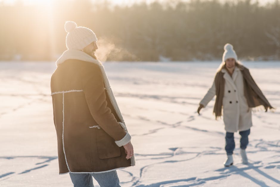 heated winter clothing - A man and woman enjoy a sunny winter day on a snowy landscape.