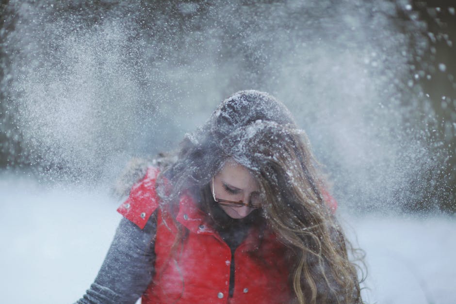 battery heated vest outdoor activities - Woman enjoying snowy weather in red vest and glasses outdoors.