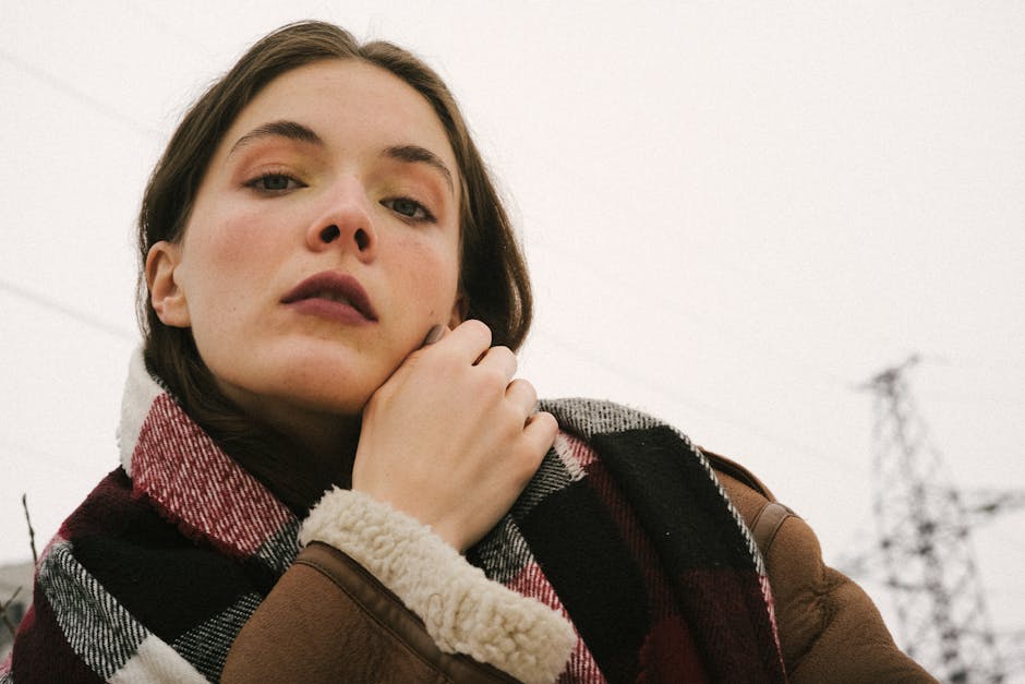 Portrait of a woman in a sheepskin coat and scarf outdoors in winter.